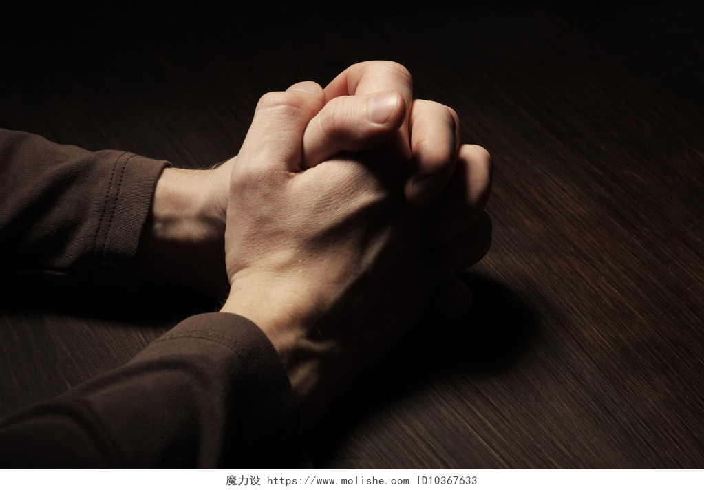 黑色背景下一个男人紧握双手在祈祷祈祷之手的图像